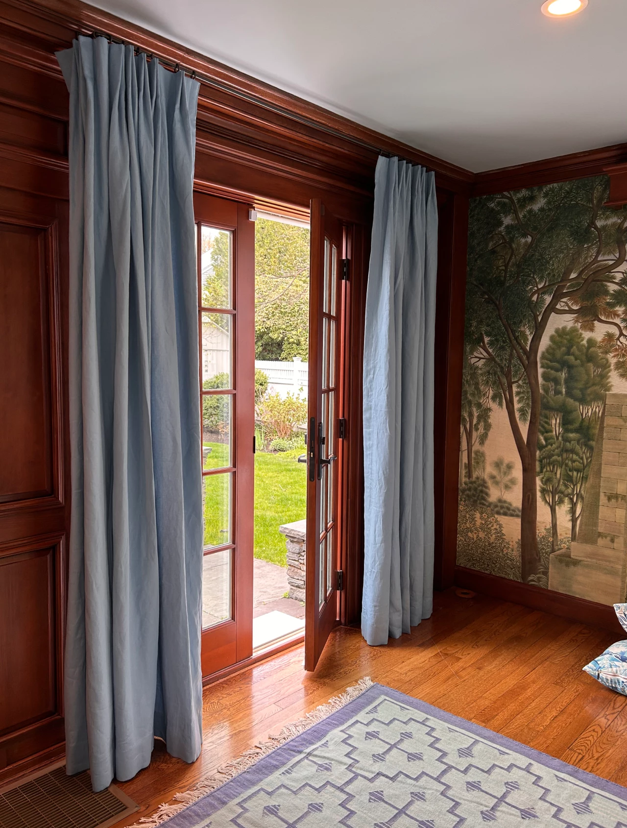 blue grey drapes against warm wood grain and pastoral wall paper